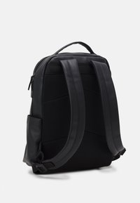 Sac à dos noir avec dos en maille rembourrée, bretelles en cuir lisse, fermeture éclair et poche latérale. Design épuré axé sur la fonctionnalité et le confort.