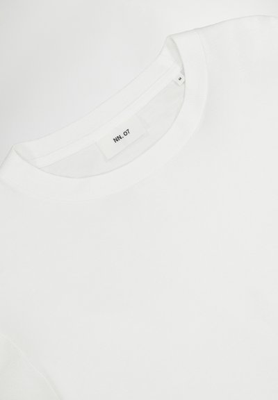 White short-sleeve t-shirt with a round neckline, ribbed texture, and a small label "NN.07" near the collar.