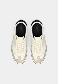 Crème leren sneakers met grijze suède accenten, ronde neus, traditioneel vetersysteem, zwarte binnenkant en contrasterende rubberen zool.