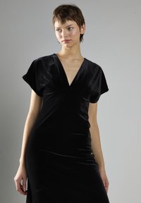 Czarna aksamitna sukienka z głębokim dekoltem w kształcie V, krótkimi rękawami typu cap i dopasowanym krojem. Gładka tekstura z delikatnym połyskiem.