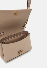 Béžová kožená kabelka s texturovaným povrchem, zlatými detaily a magnetickým zavíráním. Obsahuje vnitřní kapsu s zaoblenými okraji.