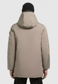 Beige, isoleret parka med hætte. Glat tekstur, mellemlang, med en sidelomme og en sort ribstrikket hue.