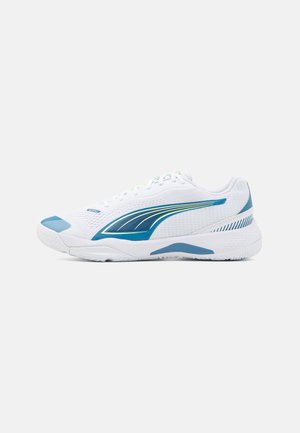 Bottines de sport blanches avec un dessus texturé, des accents bleus et un détail à rayures vertes. Elles possèdent une semelle à motifs pour l'adhérence et le soutien.