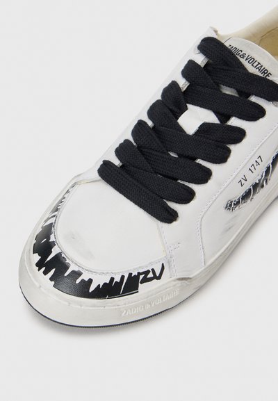 Sneaker in pelle bianca con lacci neri, caratterizzata da un motivo grafico nero sulla punta e marchio sul lato. Texture liscia.