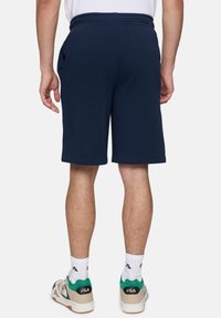 Navyblauwe, knielange shorts van een katoenmix met een elastische tailleband en zijzakken. Draagt dit met multicolore sneakers en witte sokken.