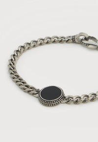 Ασημένιο βραχιόλι με αλυσίδα που διαθέτει στρογγυλό κεντρικό μαύρο λίθο με περιμετρική διακόσμηση από χάντρες και ανθεκτικό κούμπωμα.