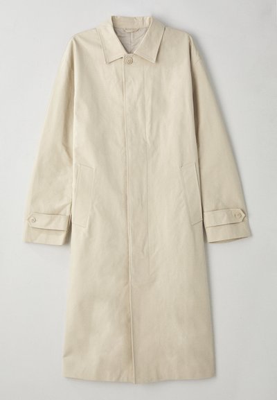 Beige, knielanger Mantel aus einer Baumwollmischung. Verfügt über einen Reverskragen, eine Frontknopfleiste und seitliche Taschen mit Klappen.