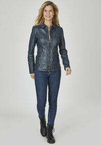 Navy Lederjacke mit Reißverschluss, Kragen und Steppdetails. Kombiniert mit blauen Jeans und schwarzen Schnürstiefeln.