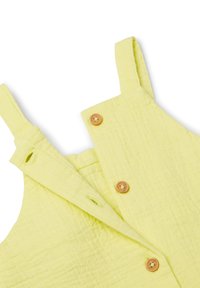 Grembiule giallo senza maniche con finitura testurizzata, caratterizzato da bottoni color sabbia lungo la parte frontale e spalline regolabili.