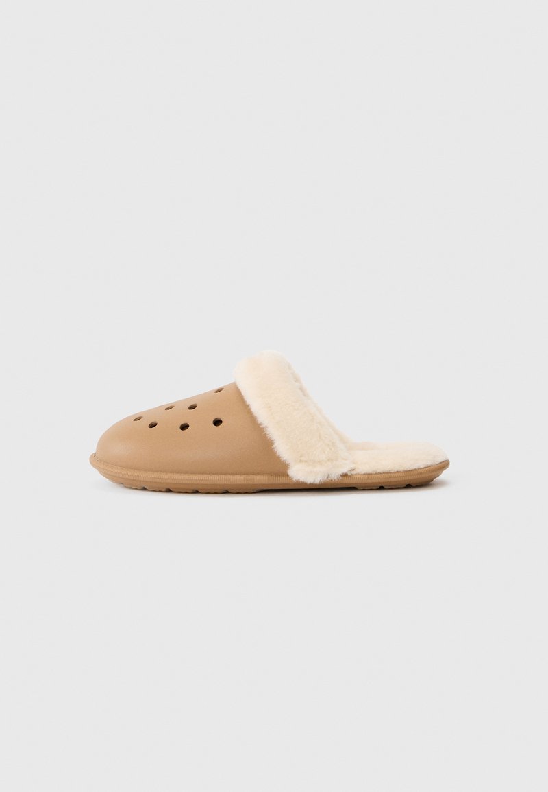 Svijetlosmeđi slip-on klompe s ventilacijskim rupama i kremastim plišom unutar i oko rubova, prikazane na jednostavnoj bijeloj pozadini.