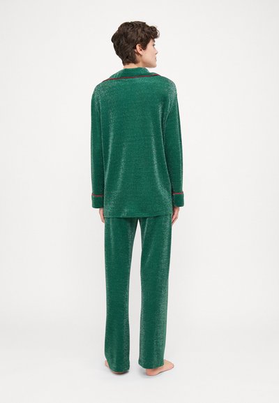 Conjunto de loungewear verde hecho de material brillante, que incluye una camisa de manga larga con cuello y pantalones a juego de corte relajado. Con detalles en rojo.