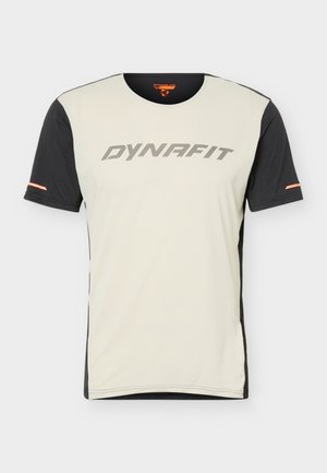T-shirt de sport à manches courtes avec un devant beige et des manches noires, logo "DYNAFIT" sur la poitrine, et petits détails orange sur les manches.