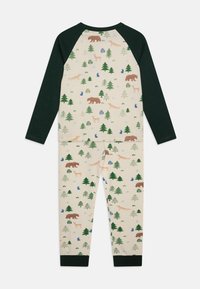 Langsleevige pyjama's in crème met groene accenten, voorzien van een natuurpatroon van beren, vossen, herten, bomen en sneeuwvlokken. Zacht, gebreid materiaal.