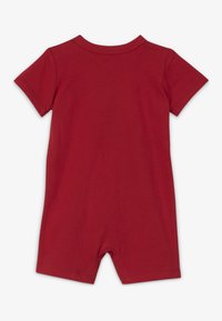 Romper corto rojo de manga corta hecho de algodón. Cuenta con un escote redondeado y piernas cortas. Textura suave con un color uniforme.