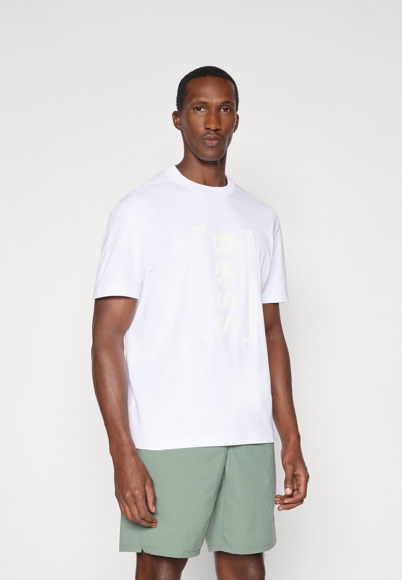 Λευκό κοντομάνικο μπλουζάκι με ανάγλυφο λογότυπο "BOSS", σε συνδυασμό με ανοιχτό πράσινο σορτσάκι, που αναδεικνύει ένα μαλακό ύφασμα και απλό σχέδιο.