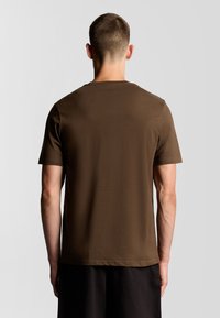 T-shirt corto marrone con colletto rotondo, realizzato in morbido cotone; presenta una leggera texture e una vestibilità comoda.