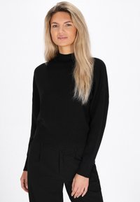 Pulover negru cu guler înalt, cu un design ajustat, margine răsucită și mâneci lungi. Textură moale și stil minimalist.