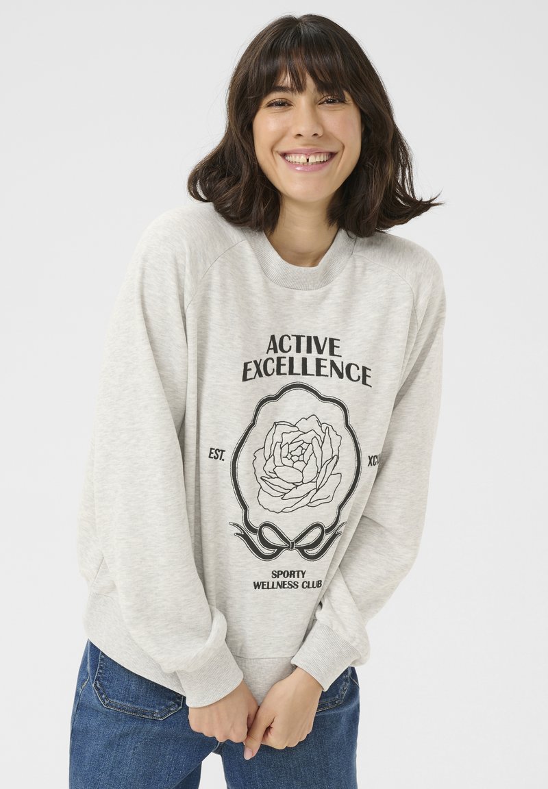 Lichtgrijze sweatshirt met een ronde halslijn en raglanmouwen. De voorkant toont zwarte tekst en een bloemenontwerp tegen de stof.