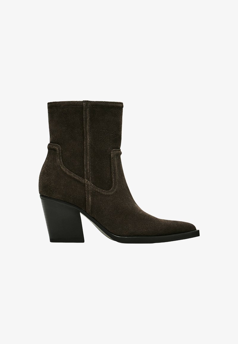 Bottine en daim marron foncé avec un bout pointu et un talon bloc noir épais, avec un détail de couture latérale.