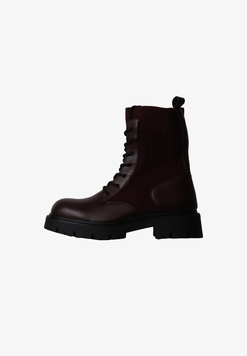 Botte en cuir marron foncé à lacets avec cheville en tissu côtelé, semelle noire épaisse et languette arrière.