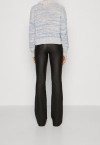 Lichtblauwe textuur crop top met geribbelde onderkant, gecombineerd met hoge zwarte uitlopende broek. Glad stof met subtiele glans.