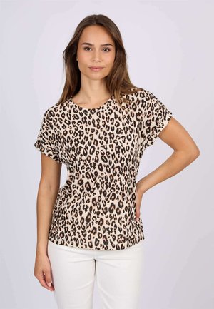 T-shirt à imprimé léopard avec des manches courtes et un col rond, fabriqué en tissu doux. L'arrière-plan est clair ; le modèle pose de manière décontractée avec les mains sur les hanches.