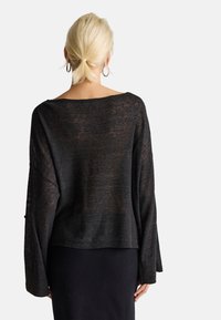 Czarny, luźny sweter z szerokimi rękawami, dekoltem w łódkę i lekko skróconym tylnym hemem. Teksturowany, półprzezroczysty materiał.