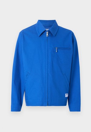 Pánská jasně modrá bunda na zip s límcem, dvěma bočními kapsami a jednou kapsou na zip na hrudi, zobrazena na jednobarevném pozadí.