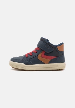Baskets montantes en marine avec des lacets rouges et un accent marron. Fabriquées en matériau semblable au cuir avec une surface texturée. Sangle Velcro.