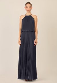 Abito maxi plissettato blu navy con scollo all'americana e vita arricciata. Il tessuto leggero crea una silhouette fluida.