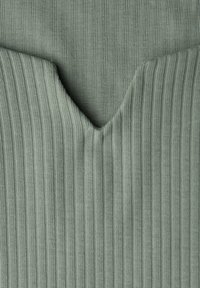 Ribbed vihreä kangas, jossa on V-muotoinen pääntie. Pinta on koristeltu kapeilla pystysuorilla linjoilla, jotka lisäävät syvyyttä ja rakennetta materiaaliin.