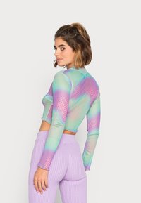 Top de manga longa, cropped e multicolorido, com um degradê de verde, roxo e rosa, apresentando padrões de bolinhas e uma bainha em pico.