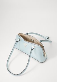 Sac à main bleu clair avec une texture brillante, fermeture éclair, deux anses et quincaillerie dorée. L'intérieur est doté d'une doublure à motif.
