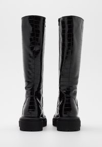 Czarne, wysokie do kolan botki z błyszczącej tekstury krokodyla. Posiadają mocną czarną podeszwę oraz suwak z boku, co ułatwia zakładanie.