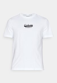 Hvit bomull T-skjorte med en svart Calvin Klein-logo sentrert på brystet, korte ermer og rund hals.