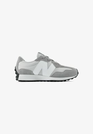 Baskets de sport grises et blanches en suède et mesh, avec fermeture à lacets et semelle noire texturée, orientées vers la gauche sur fond blanc.