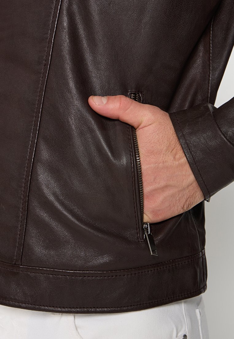Bruine leren jas met een ritszak en een gladde textuur; beschikt over een getailleerd ontwerp en contrasterende stikseldetails.