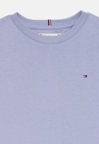 Lys lilla t-shirt med rund hals, korte ærmer og et lille logo i rød, hvid og blå på venstre bryst. Glat bomuldsstof.