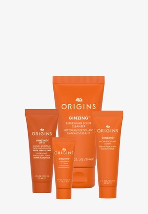 Quatre tubes orange de soins pour la peau Origins GinZing, incluant une crème hydratante teintée, une crème pour les yeux, un nettoyant exfoliant rafraîchissant et un sérum illuminateur.