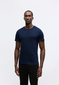 T-shirt girocollo blu navy realizzata in cotone, con maniche corte e vestibilità slim. Texture liscia con dettagli minimi.