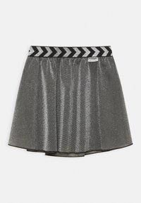 Grå glittrande kjol med ett svart och vitt chevron-mönstrat elastiskt midjeband. Har en utfläkt design och en slät textur för ökad rörelse.