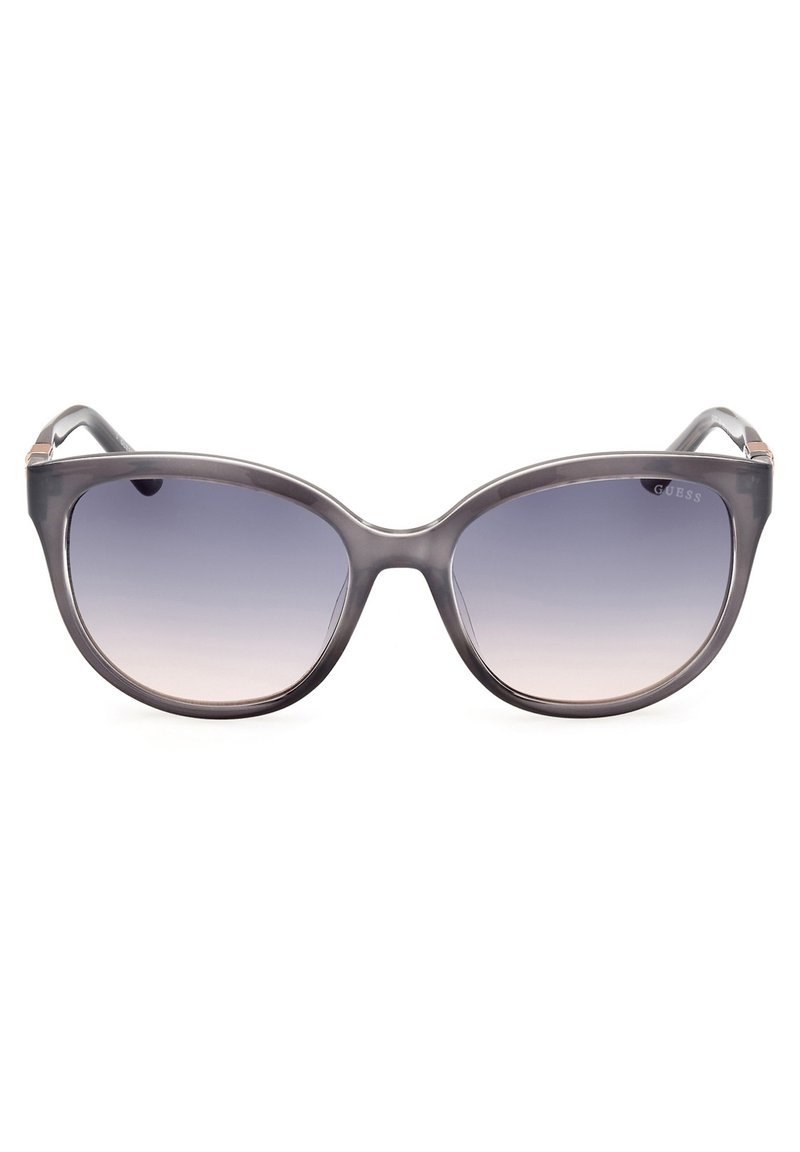 Gafas de sol estilo cat-eye con lentes de sombra graduada oscura. Hechas de plástico gris brillante con detalles en plata en las varillas. Diseño ligero y elegante.