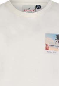 Biała bawełniana koszulka z kwadratowym nadrukiem przedstawiającym scenę plaży i palmy. Zawiera tekst "RETOUR JEANS" poniżej obrazu.