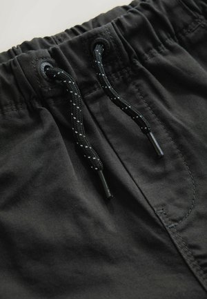 Czarne szorty z elastycznym pasem i sznurkiem, z czarno-białym, nakrapianym wzorem. Gładka tekstura materiału.