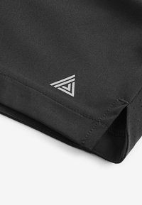 Zwarte sportshorts met een zachte textuur, voorzien van een reflecterende geometrische logo en geperforeerde details aan de zoom.