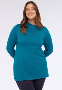 Teal långärmad tunika i mjukt material, med en ribbad krage med knappdetaljer och sidoklyftor i fållen för ökad komfort.