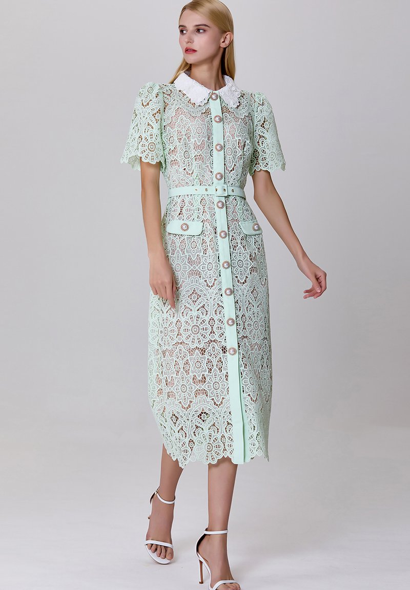 Robe en dentelle vert menthe avec un col blanc, des manches courtes bouffantes, une fermeture à boutons sur le devant et une ceinture assortie ; motifs floraux et détail d'ourlet festonné.