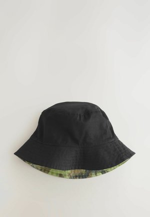 Sort bøttehat med bred skygge. Indersiden har et grønt camouflage-mønster. Lavet af slidstærkt stof med synlige syning detaljer.