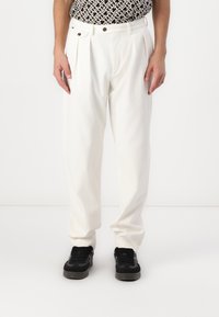 Witte geplooide broek van katoen, met een hoge taille, zijzakken en een losse pasvorm, gecombineerd met zwarte sneakers.
