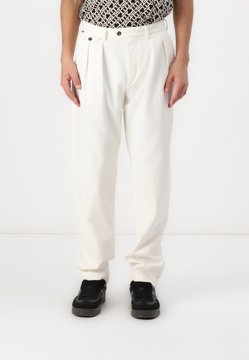 Witte geplooide broek van katoen, met een hoge taille, zijzakken en een losse pasvorm, gecombineerd met zwarte sneakers.